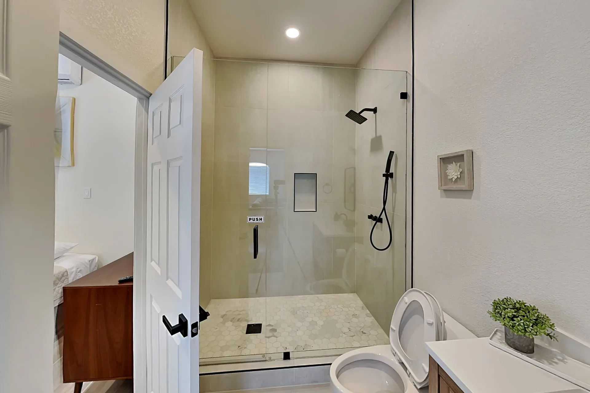 Full bathroom with a wide walk-in shower on a hexagon-tiled floor, opening directly off its bedroom