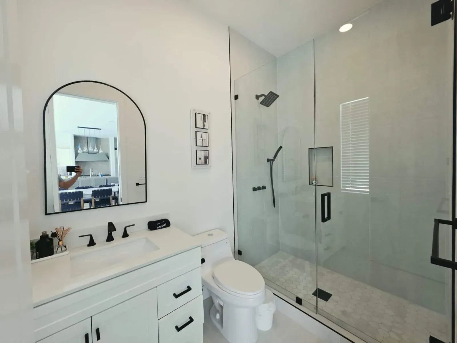 Full bathroom with an arched mirror, quartz vanity and glass walk-in shower