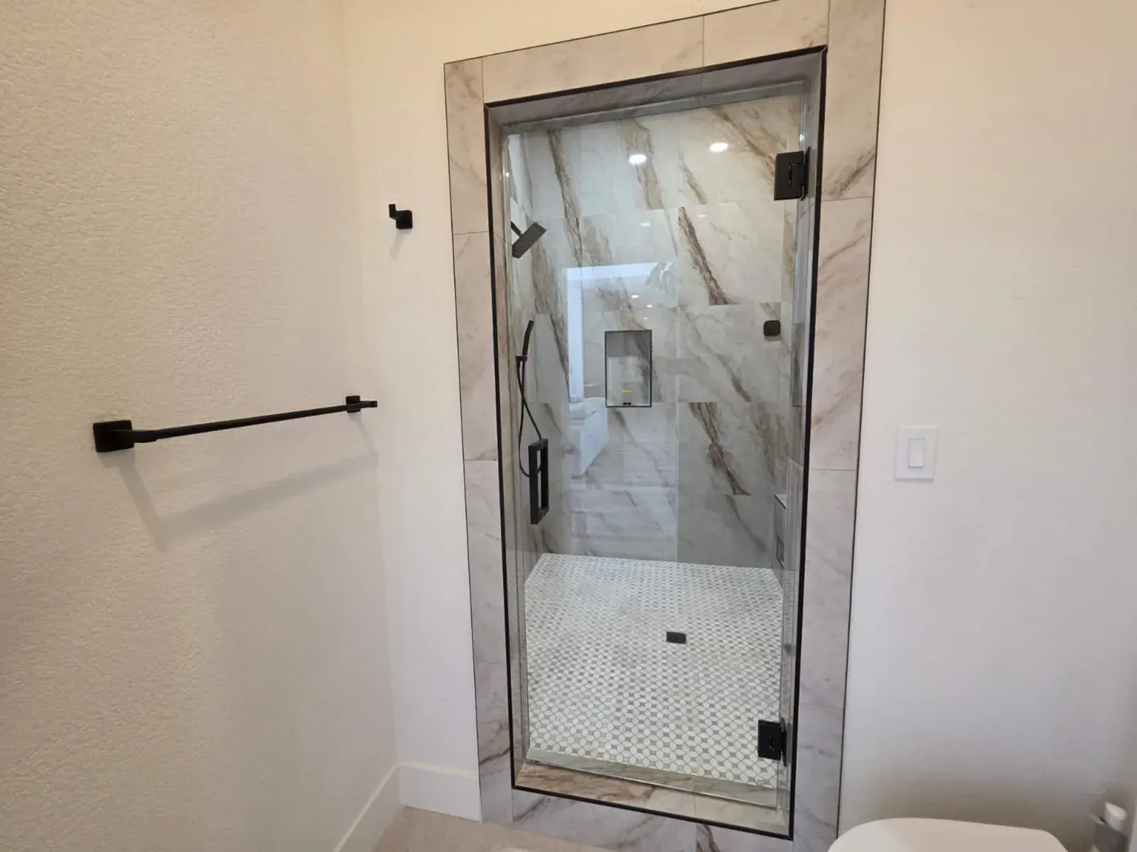 Bathroom with glass-enclosed marble shower and oak vanity