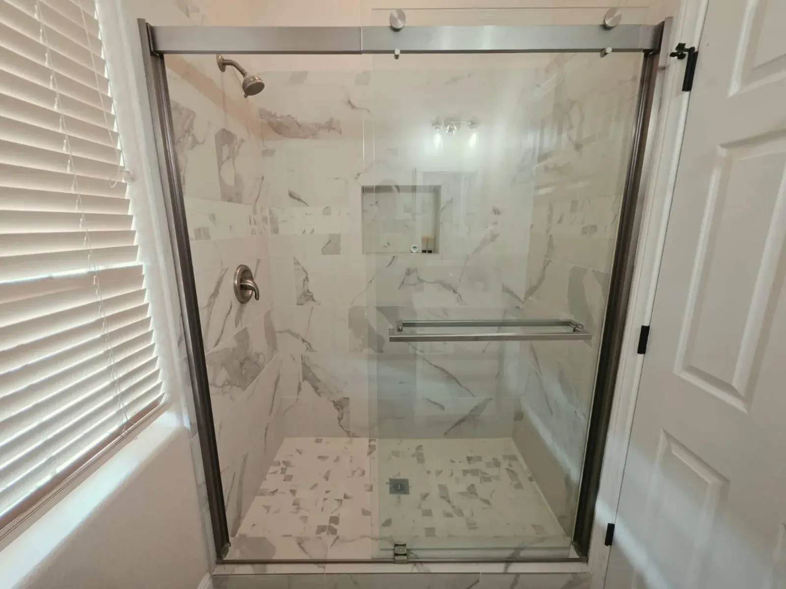 Full bathroom with a marble-tiled shower behind sliding glass