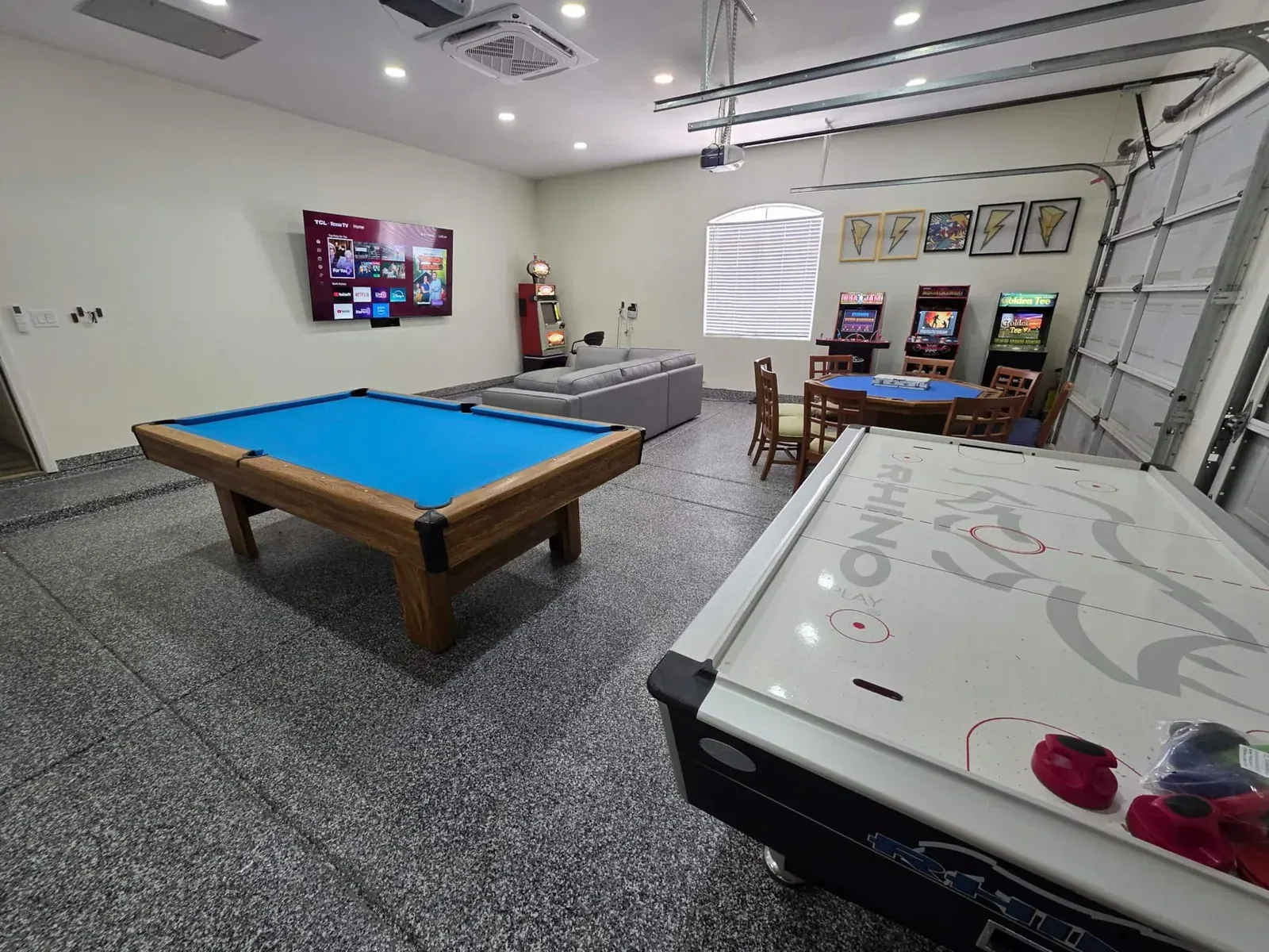 Game room with professional pool table, air hockey, poker table, slot machine, arcade cabinets and an 86-inch screen