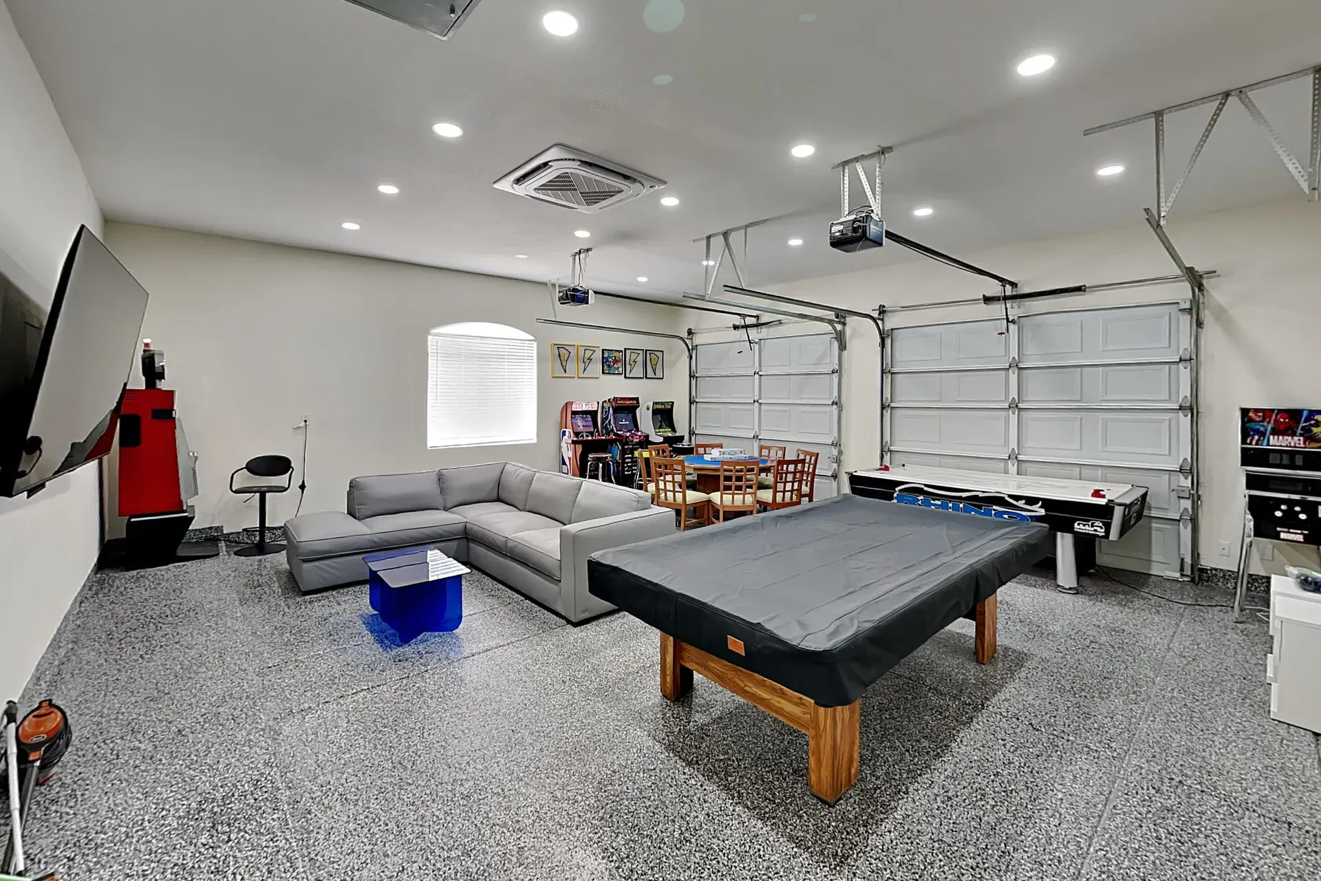The game room — full-size pool table, air hockey, a felt poker table, arcade cabinets and a slot machine