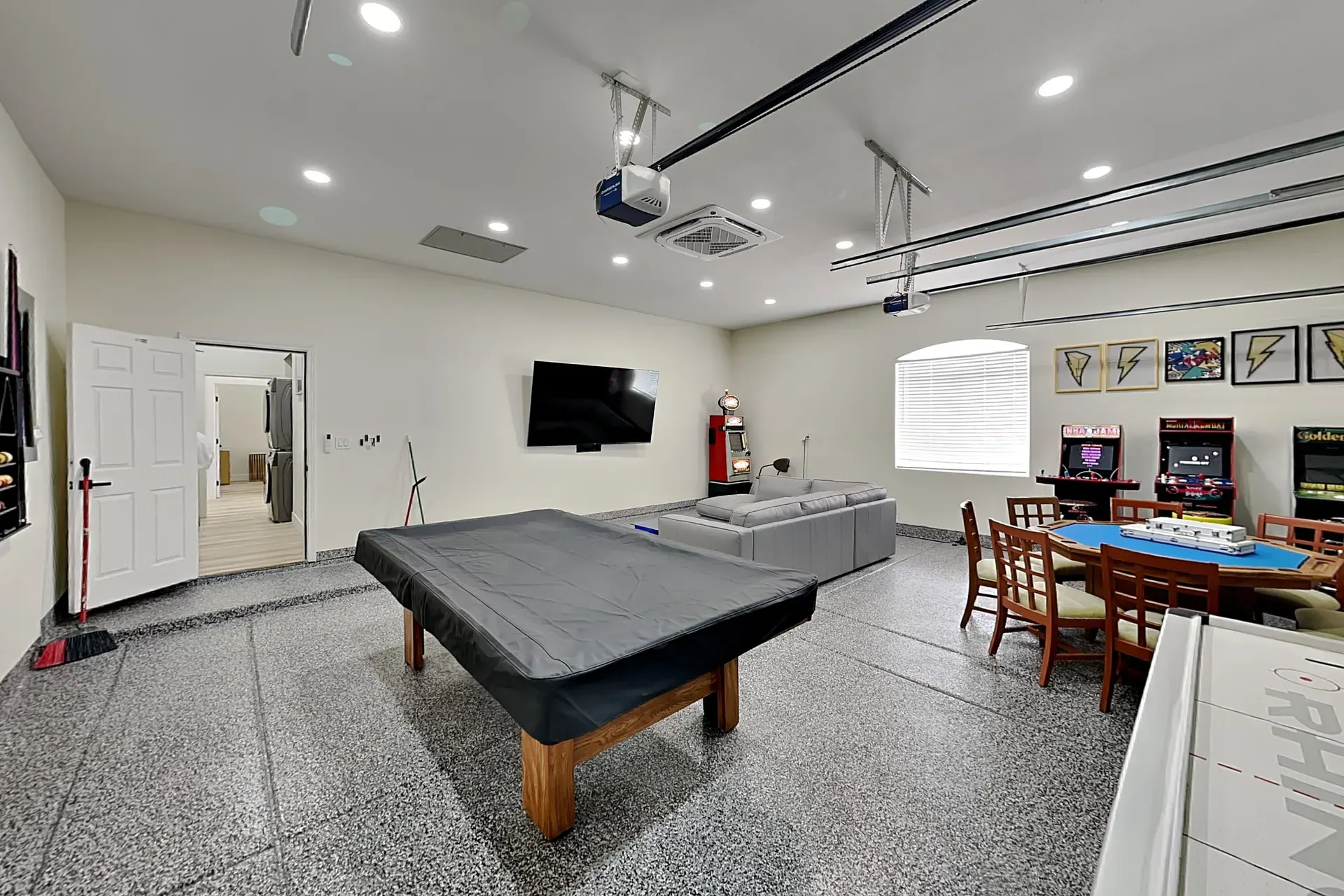 The game room from the other end, the row of arcade cabinets and the poker table along one wall