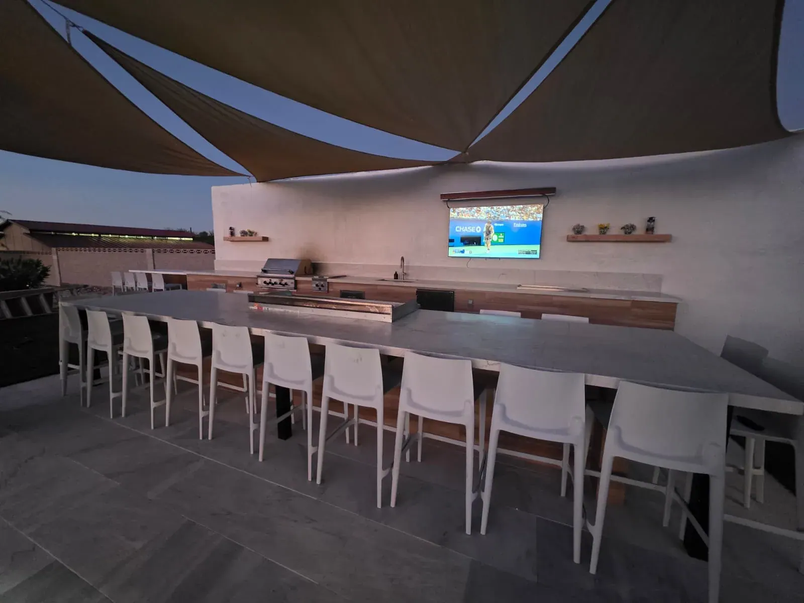 The hibachi dining bar at dusk — the griddle running down a long stone counter ringed by twenty chairs