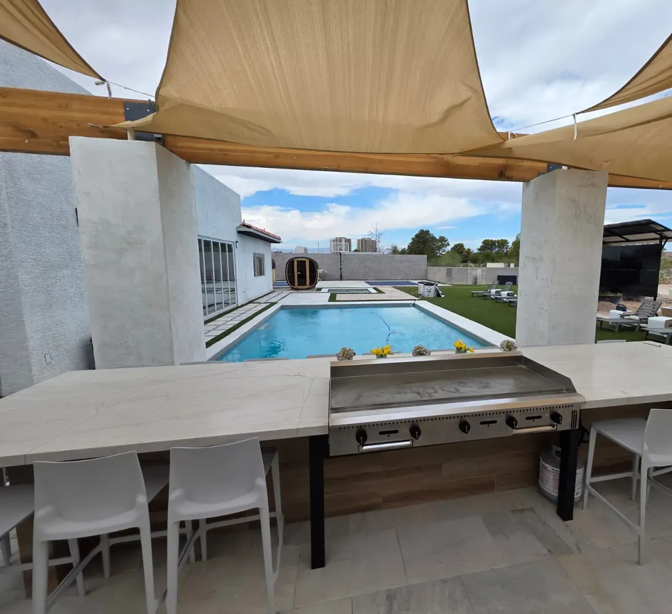 The hibachi griddle set into the outdoor kitchen bar, looking across the pool