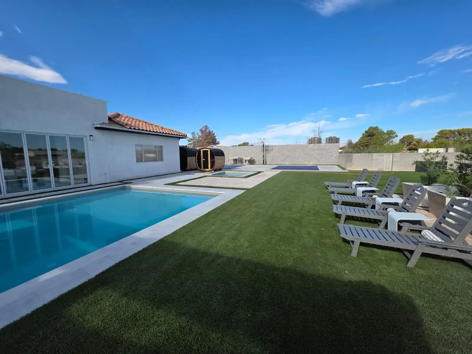 The pool and lounger-lined lawn, with the barrel saunas in the distance