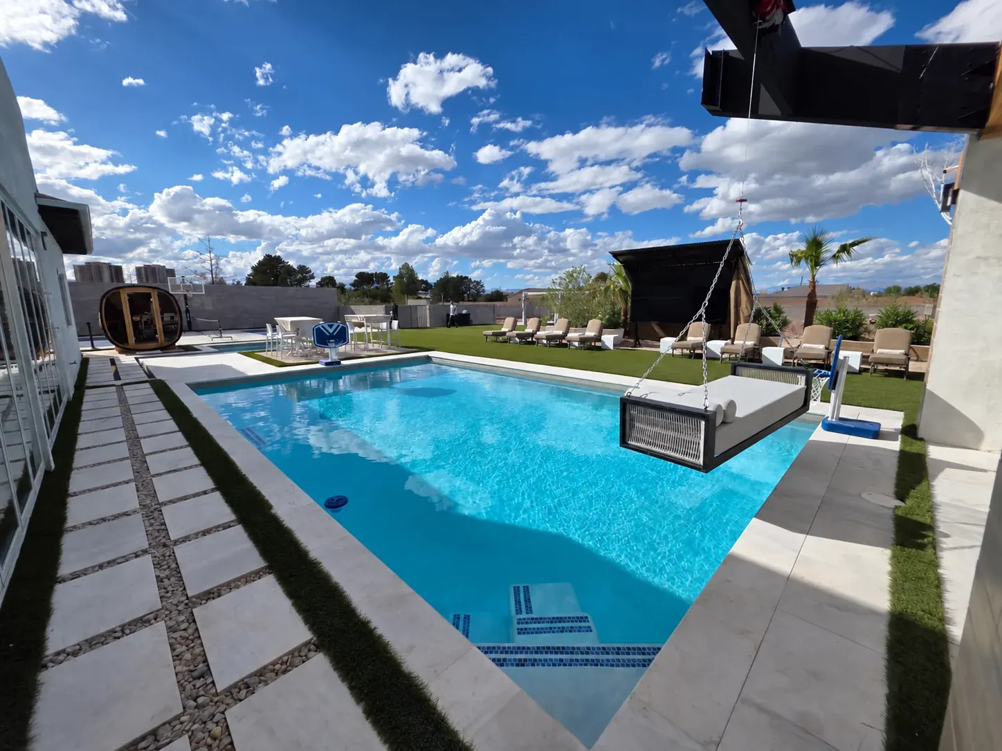 A cushioned swing bench hung on chains from the pergola, suspended over the corner of the pool