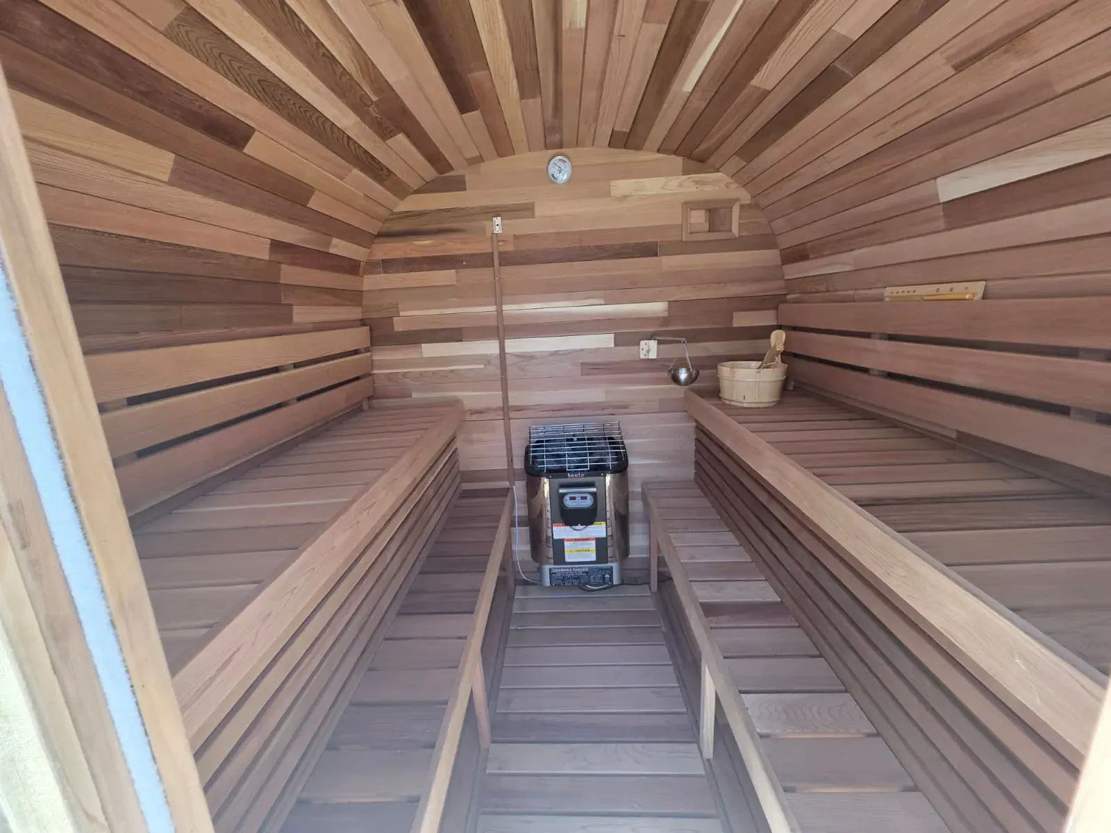 Inside the second dry sauna — banded cedar walls, benches down both sides and the heater at the far end