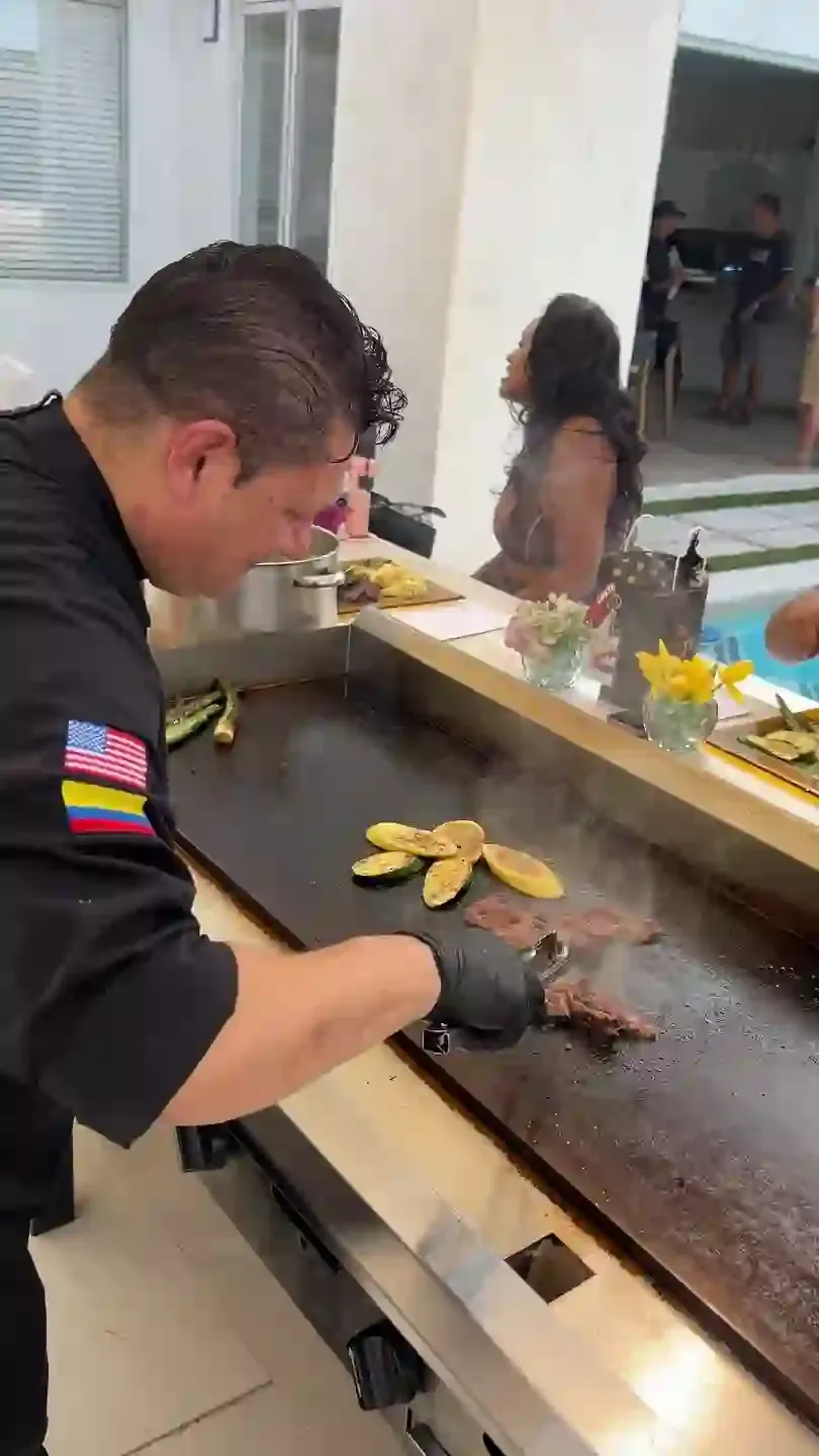 The chef working the 60-inch hibachi griddle, guests seated along the bar behind