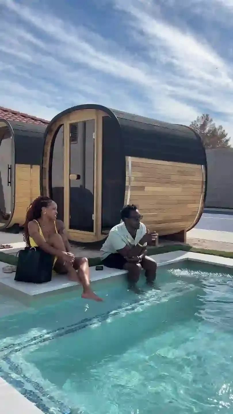 Two guests sitting on the deck beside a cedar barrel sauna and the plunge