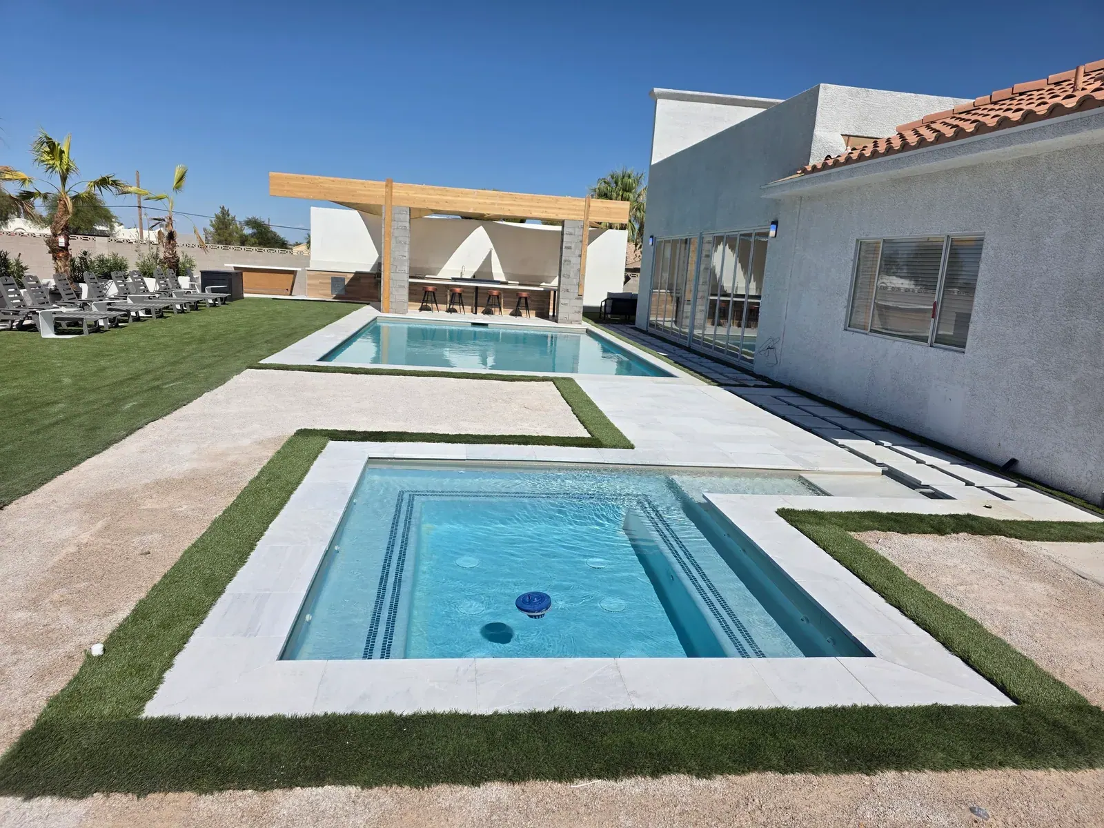 The heated spa set into the deck, with the pool and outdoor kitchen behind